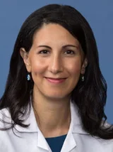 Leila Parand, MD, female in white coat, smiling for professional portrait.