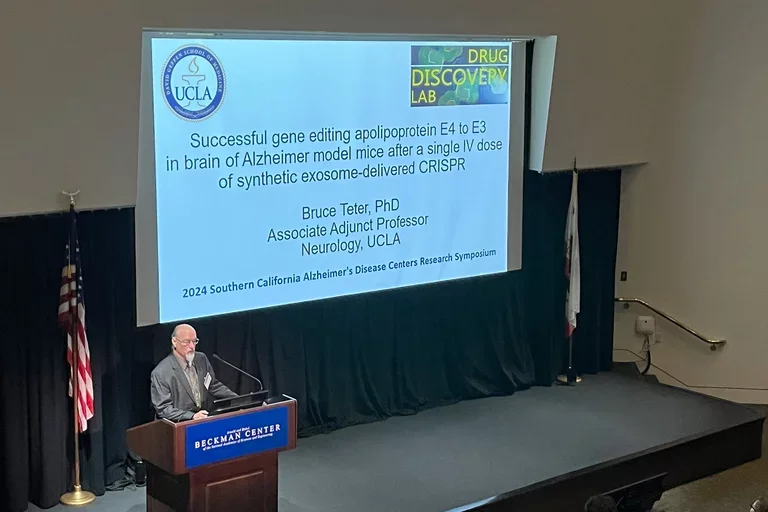 Dr. Bruce Teter, male, on the podium, presenting at the 2024 SoCal Alzheimer's Disease Centers Research Symposium.