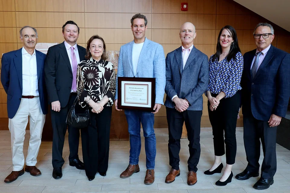 A male junior faculty received a research award, surrounding by donor, faculties and members of Alzheimer's Los Angeles.