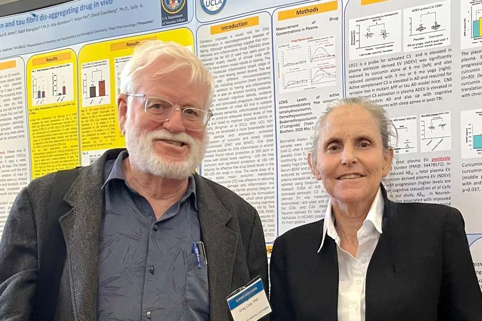 Dr. Greg Cole and Dr. Sally Frautschy standing in front of their poster board 