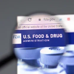 US Food and Drug magnified with medication in the background.
