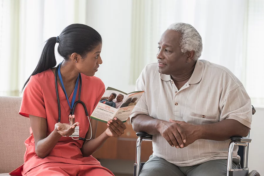 A nurse providing an elderly black man with information