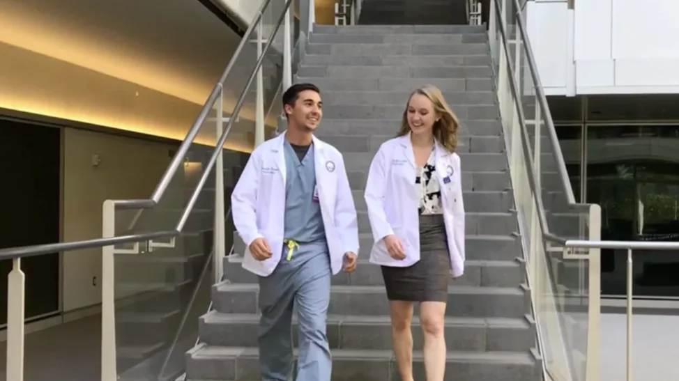 Two medical students walk down the stairs into the courtyard at Geffen Hall, deep in conversation
